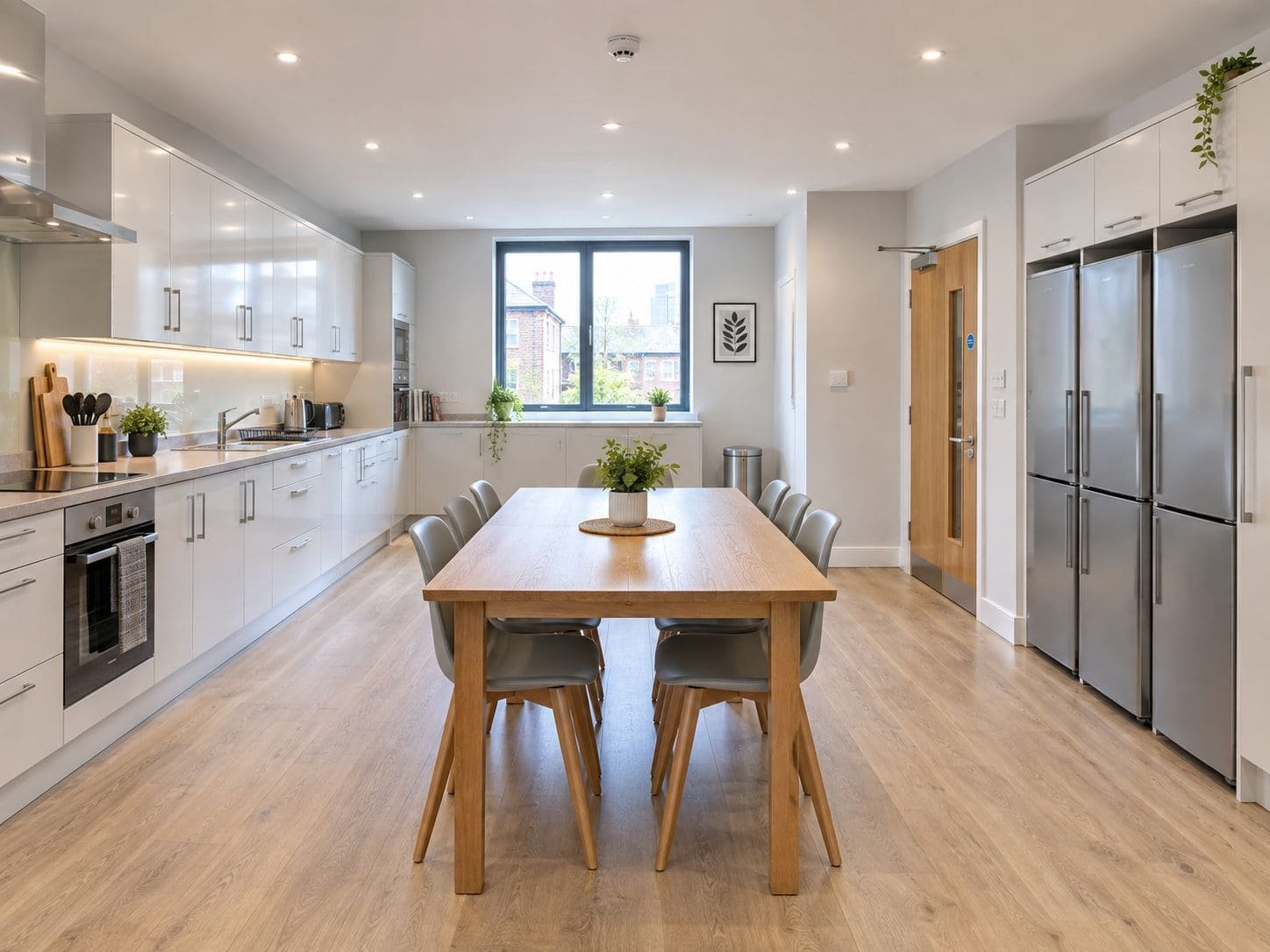 A shared HMO kitchen and dining room with a long table and several fridges